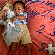 Kay Veon Boren is registered to the contest to win money with this photo: baby, child, infant, toddler, blanket, stuffed_animal, toy, clothing, shorts, shirt, curly_hair, lying_down, carpet, floor, indoor, person, cute, soft_toy, playtime, relaxing