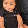 Kay Veon Boren joined the competition — help win amazing prizes! toddler, child, smile, curly_hair, black_onesie, nike_logo, sitting, couch, indoor, happy, baby, skin, face, hand, furniture, young_child, portrait, casual, relaxed, cute