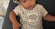 Kay Veon Boren is registered to the contest to win money with this photo: baby, brown_skin, chair, checkered_clothing, child, cozy, curly_hair, eyes, face, fashion, hat, home, indoors, infant, looking_at_camera, mouth, overalls, photography, portrait, sitting
