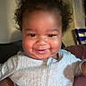 Kay Veon Boren joined the competition — help win amazing prizes! baby, cheeks, child, closeup, clothing, curly_hair, dark_hair, eyes, face, gray_romper, happy, held, home, indoor, infant, photography, portrait, seated, smiling, warm_lighting