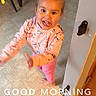 toddler, child, pink_clothing, dinosaur_pattern, barefoot, indoor, floor, tile_floor, playful, tongue_out, happy, person, sun_doodle, text_overlay, morning, wall, door, motion_blur, home, cute