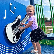 Veronica is registered to the contest to win money with this photo: toddler, child, playground, guitar, musical_notes, blue, green, smiling, outdoor, summer, sandals, skirt, purple_shirt, play_equipment, happy, daytime, music, fun, person, recreation
