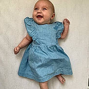Neige a rejoint le concours — aidez-le/la à gagner de superbes lots ! arm, baby, barefoot, blue_dress, child, clothing, cute, expression, face, happy, human, indoors, infant, leg, lying_down, one_person, portrait, skin, smiling, young