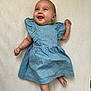 arm, baby, barefoot, blue_dress, child, clothing, cute, expression, face, happy, human, indoors, infant, leg, lying_down, one_person, portrait, skin, smiling, young