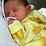 baby, newborn, sleeping, yellow_clothing, onesie, infant, person, hand, car_interior, window, closeup, peaceful, cute, resting, skin, head, ear, soft, tender, caring
