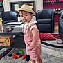 Léon participe au concours pour gagner de l'argent avec cette photo : toddler, child, hat, pacifier, pink_overalls, barefoot, living_room, toy_blocks, carpet, armchair, table, wooden_tray, curious, indoor, furniture, colorful, floor, pillow, beige, person