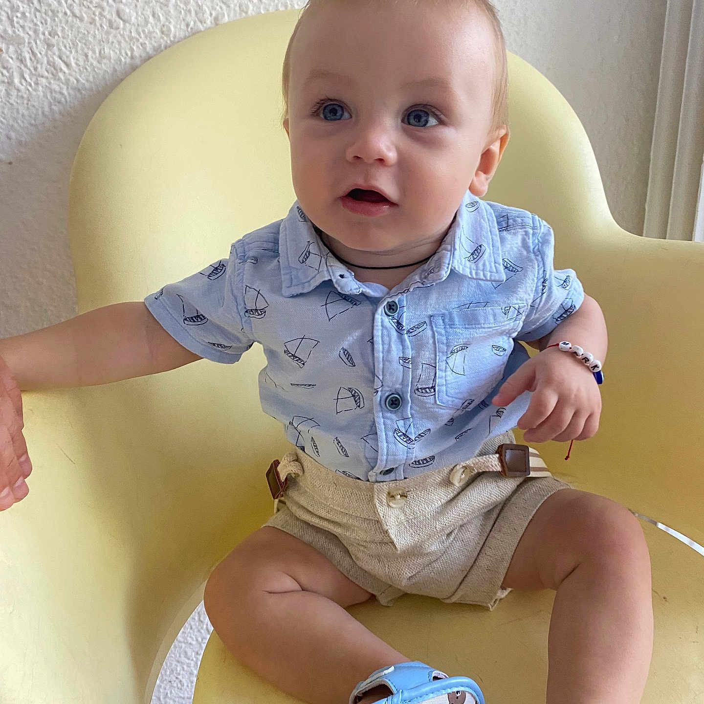 Vartic Mark a rejoint le concours — aidez-le/la à gagner de superbes lots ! baby, bear_prints, beige_shorts, blue_eyes, blue_sandals, casual_clothing, child, curious_expression, cute, footwear, hand_holding, indoor, light_blue_shirt, person, portrait, sailboat_print, seated, soft_lighting, suspenders, yellow_chair