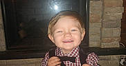 Alex joined the competition — help win amazing prizes! blanket, bow_tie, checkered_shirt, child, clothing, cute, face, fireplace, floor, hands, happy, home, indoor, person, portrait, smiling, stone_wall, toddler, toy, vest