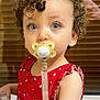 baby_accessory, blinds, blue_eyes, child, closeup, curly_hair, cute, expression, face, holding_object, indoor, infant, pacifier, person, portrait, red_dress, skin, toddler, window, young_child