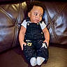 toddler, child, baby, overalls, black_clothing, white_shirt, socks, leather_couch, seated, indoor, cute, curious_expression, portrait, young_child, furniture, home, casual_clothing, small_hands, short_hair, relaxed
