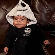 Asaiah joined the competition — help win amazing prizes! baby, infant, child, hood, skull_design, black_outfit, cute, dimples, leather_couch, indoor, portrait, cozy, clothing, fashion, young_child, expression, sitting, person, face, candid