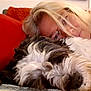 dog, woman, blonde_hair, glasses, couch, pillow, red_pillow, snuggling, resting, indoor, pet, fluffy_dog, face, close_up, companion, relaxing, comfort, furniture, home, casual
