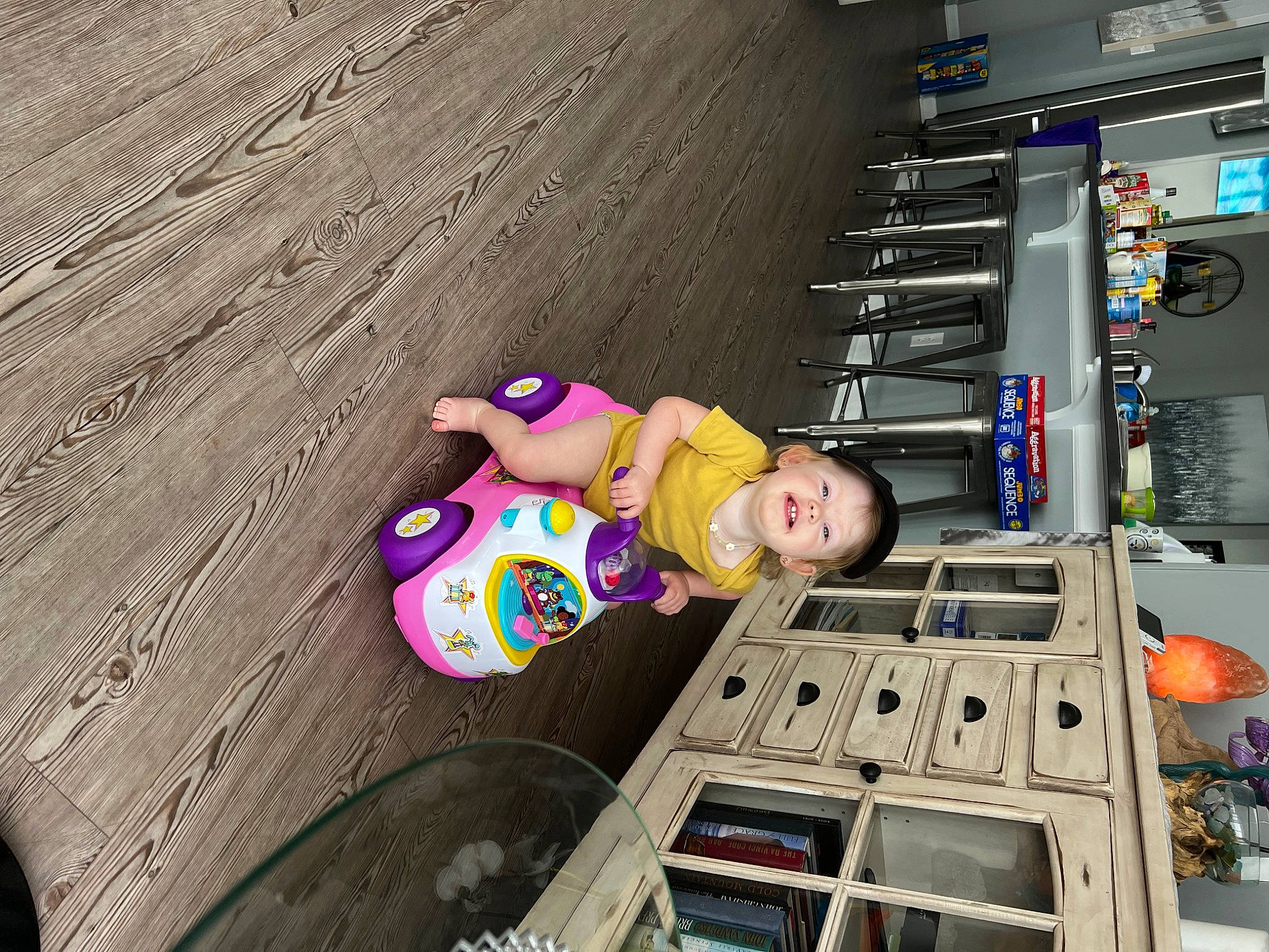 Gracelynn is registered to the contest to win money with this photo: audio_equipment, automotive_design, building, engineering, flooring, fun, hat, human_leg, leisure, machine, person, recreation, smile, t_shirt, thigh, tire, toddler, toy, wheel, wood