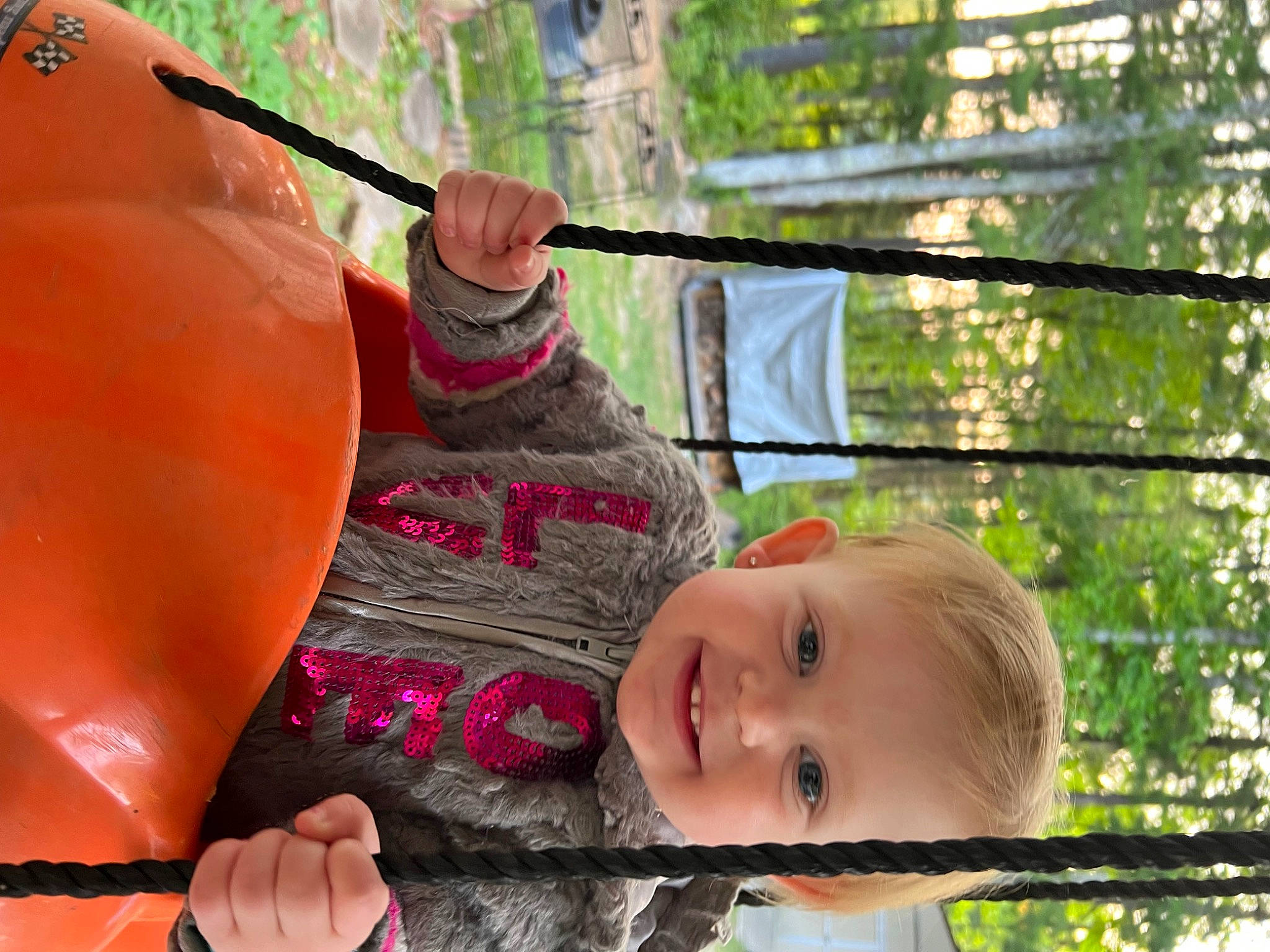 Gracelynn is registered to the contest to win money with this photo: boats_and_boating_equipment_and_supplies, child, fun, grass, happy, hat, joy, leaf, leisure, outdoor_play_equipment, people, people_in_nature, person, plant, recreation, sitting, smile, summer, swing, toddler