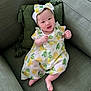 baby, infant, smiling, lemon_print, dress, headband, bow, couch, green_pillow, tassel, legs, toes, sitting, indoor, portrait, cute, happy, fabric, pattern, person