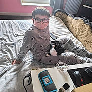 Neige a rejoint le concours — aidez-le/la à gagner de superbes lots ! bed, black_and_white_cat, cat, child, cozy, curtain, desk, glasses, headboard, home, indoor, lighting, mouse, pajamas, phone, pink_wall, radiator, relaxed, sitting, window