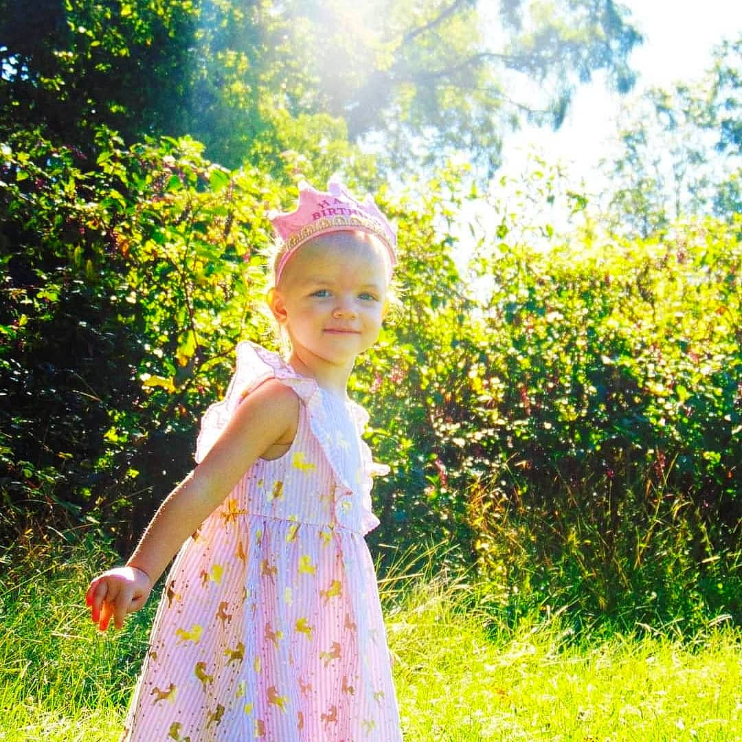 Grace is registered to the contest to win money with this photo: baby, baby_toddler_clothing, day_dress, electric_blue, fun, grass, grass_family, grassland, happy, joy, leaf, magenta, meadow, one_piece_garment, pattern, people_in_nature, person, plant, smile, sunlight