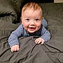 baby, smiling, blue_clothing, bed, blanket, infant, cute, happy, child, toddler, indoors, portrait, face, skin, sleepwear, hands, expression, lying_down, young_child, cozy
