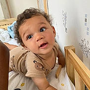 Lou participe au concours pour gagner de l'argent avec cette photo : arm, baby, bed, bedding, child, curious, curly_hair, cute, expression, face, head, indoor, looking_up, person, playful, room, skin, sleepwear, toddler, wooden_crib