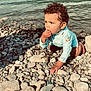 barefoot, blue_shirt, child, crouching, curly_hair, daytime, exploring, lake, long_sleeve, nature, outdoor, pebbles, person, rocky_shore, shoreline, small_rocks, summer, sunlight, toddler, water