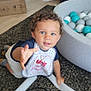 baby, ball_pit, bib, blue_eyes, carpet, child, clothing, couch, curious, curly_hair, cute, floor, home, indoor, person, play, reaching_hand, sock, toddler, toy