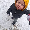 child, toddler, snow, winter_clothing, orange_hood, black_jacket, gloves, blue_eyes, outdoor, footwear, curious_expression, standing, holding_hands, cold_weather, snowy_ground, winter, person, cute, face, portrait