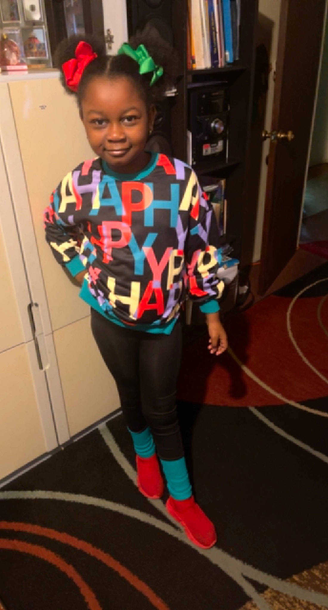 Aliyah is registered to the contest to win money with this photo: active_pants, child, costume, electric_blue, flooring, fun, human_leg, joy, knee, leggings, pattern, person, room, sleeve, smile, sock, sportswear, standing, sweatpant, t_shirt