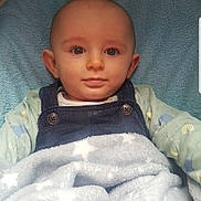 Teddy is registered to the contest to win money with this photo: baby, infant, blanket, blue_blanket, clothing, denim_overalls, face, eyes, head, ears, towel, stroller, bassinet, portrait, child, cute, soft_texture, indoor, resting, calm