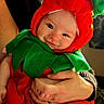 adult, baby, chair, child, closeup, costume, cozy, family, green_clothing, hands, happy, hat, holding, indoors, infant, leaf, portrait, red_clothing, smiling, strawberry_costume