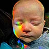 baby, infant, sleeping, closed_eyes, face, portrait, rainbow, colored_light, reflection, cozy, clothing, gray_shirt, closeup, indoors, soft_lighting, serene, peaceful, young_child, head, photography