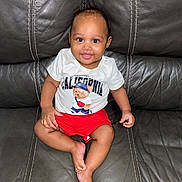 Tylan joined the competition — help win amazing prizes! baby, child, smiling, tshirt, shorts, sitting, leather_couch, happy, cute, indoors, person, infant, portrait, casual_clothing, skin, feet, hand, face, young, comfortable