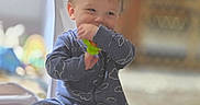 George joined the competition — help win amazing prizes! baby, blue_clothing, blurred_background, carpet, child, cozy, cute, face, happy, home, indoor, onesie, person, playful, sitting, smiling, soft_light, toddler, toy, young_child