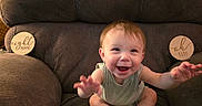 George is registered to the contest to win money with this photo: baby, armchair, smiling, happy, indoor, milestone_marker, wooden_sign, clothing, socks, child, person, furniture, seat, celebration, milestone, cute, infant, portrait, baby_girl, sitting