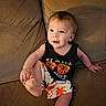 toddler, child, smiling, couch, clothing, tank_top, shorts, indoor, face, person, foot, happy, sitting, palm_tree, patterned_clothing, cute, infant, casual, relaxed, young_child