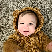 George joined the competition — help win amazing prizes! baby, brown, carpet, child, childhood, costume, cozy, cute, face, fur_clothing, fuzzy, happy, hood, indoor, infant, person, portrait, smile, texture, young