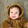 baby, brown, carpet, child, childhood, costume, cozy, cute, face, fur_clothing, fuzzy, happy, hood, indoor, infant, person, portrait, smile, texture, young