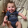baby, smiling, onesie, child, infant, plush_toy, baby_chair, patterned, happy, cute, indoor, person, face, young_child, seated, reaching, clothing, comfort, infant_toddler, portrait