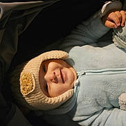 Youcef a rejoint le concours — aidez-le/la à gagner de superbes lots ! baby, baby_clothes, blanket, blue_outfit, child, cozy, cute, face, hand, hat, indoor, infant, knitted_hat, portrait, resting, sleeping_bag, smiling, soft_texture, warm_clothing, zipped_jacket