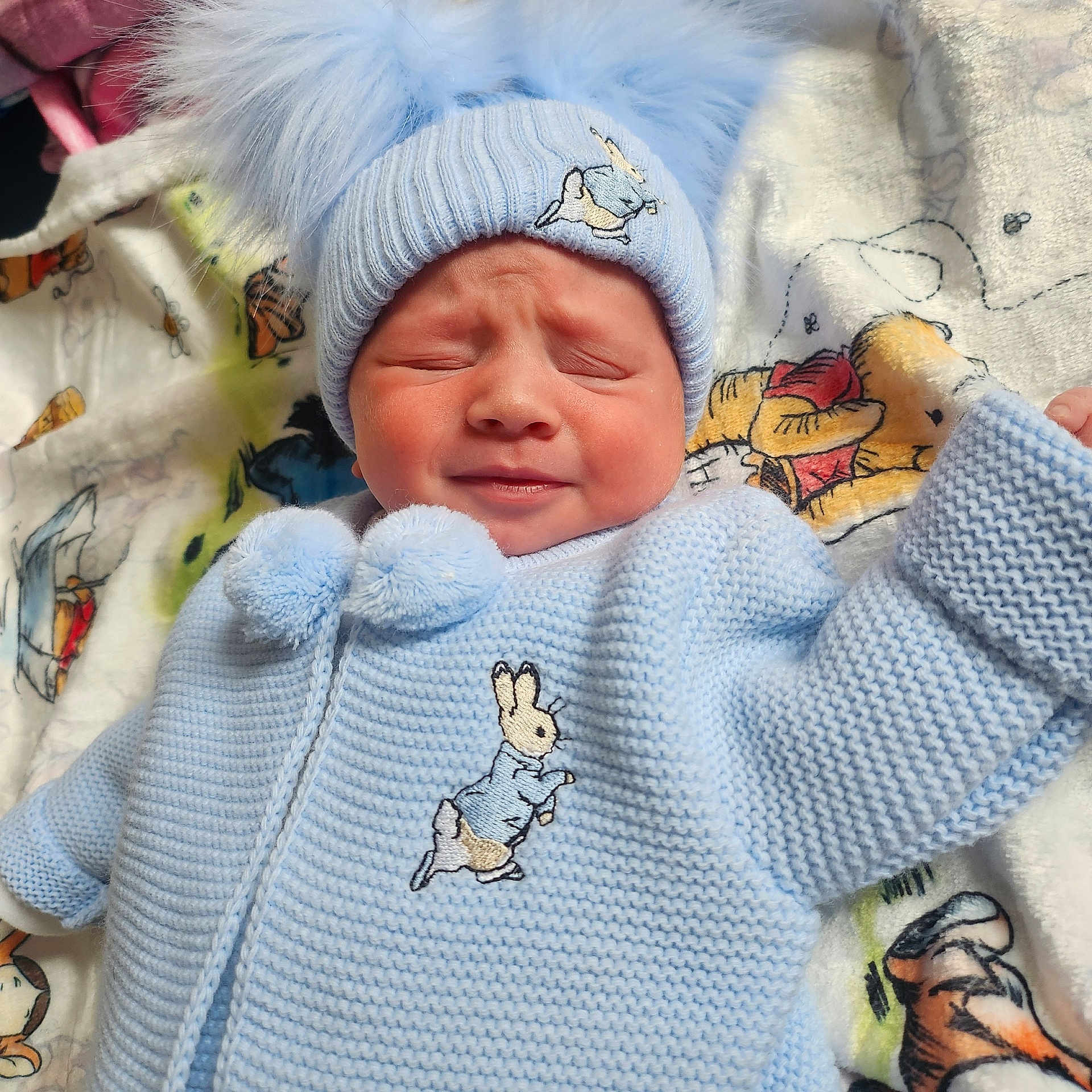Jaxon-John joined the competition — help win amazing prizes! baby, infant, blue_clothing, knitwear, hat, pom_poms, blanket, winnie_the_pooh, cartoon, cute, face, expression, indoor, child, newborn, person, soft, warm, lying_down, cozy