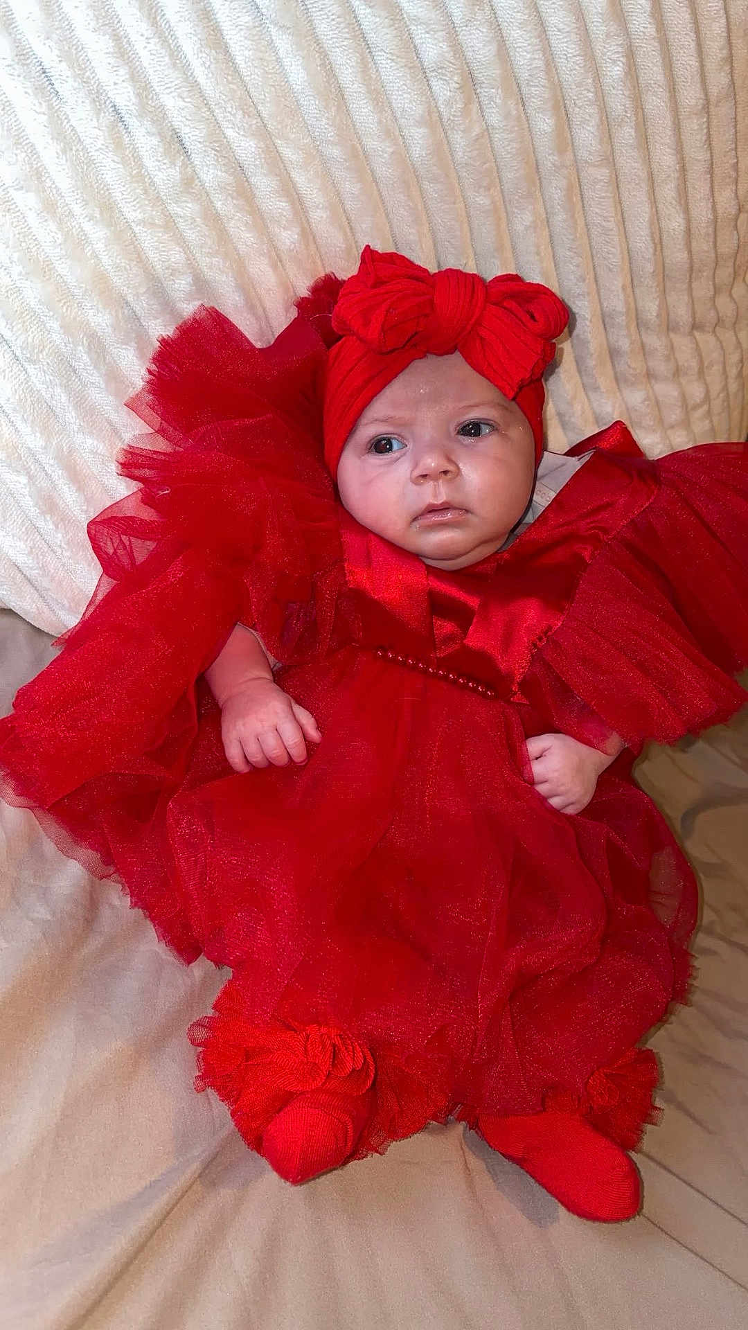 Jersey participe au concours pour gagner de l'argent avec cette photo : baby, infant, red_dress, headband, bow, socks, blanket, couch, portrait, cute, child, indoors, soft_texture, fashion, adorable, sitting, clothing, person, young, expression