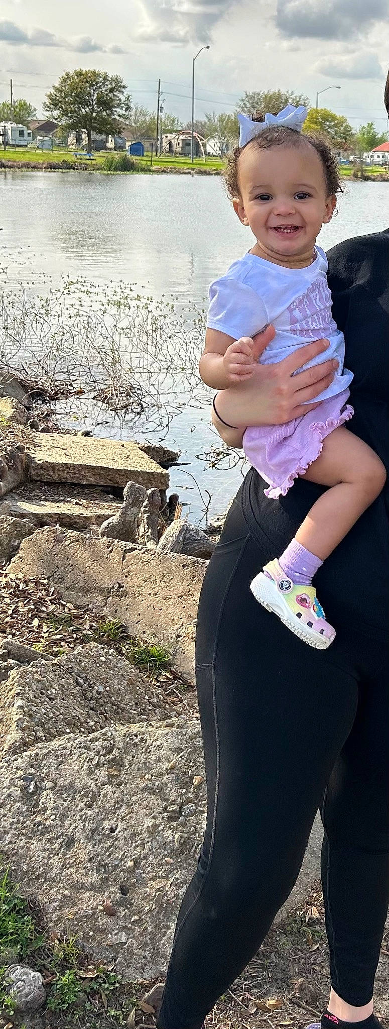 Maliyah is registered to the contest to win money with this photo: arm, child, cool, eyewear, fun, grass, happy, hat, human_leg, joy, knee, lake, leg, person, plant, recreation, shorts, soil, sportswear, t_shirt