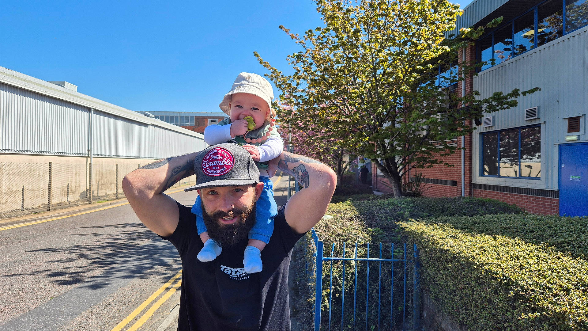 Bjørn is registered to the contest to win money with this photo: baby, baseballcap, cap, city, clothing, face, fence, hat, head, hedge, neighborhood, person, photography, plant, portrait, road, street, t_shirt, tree, urban