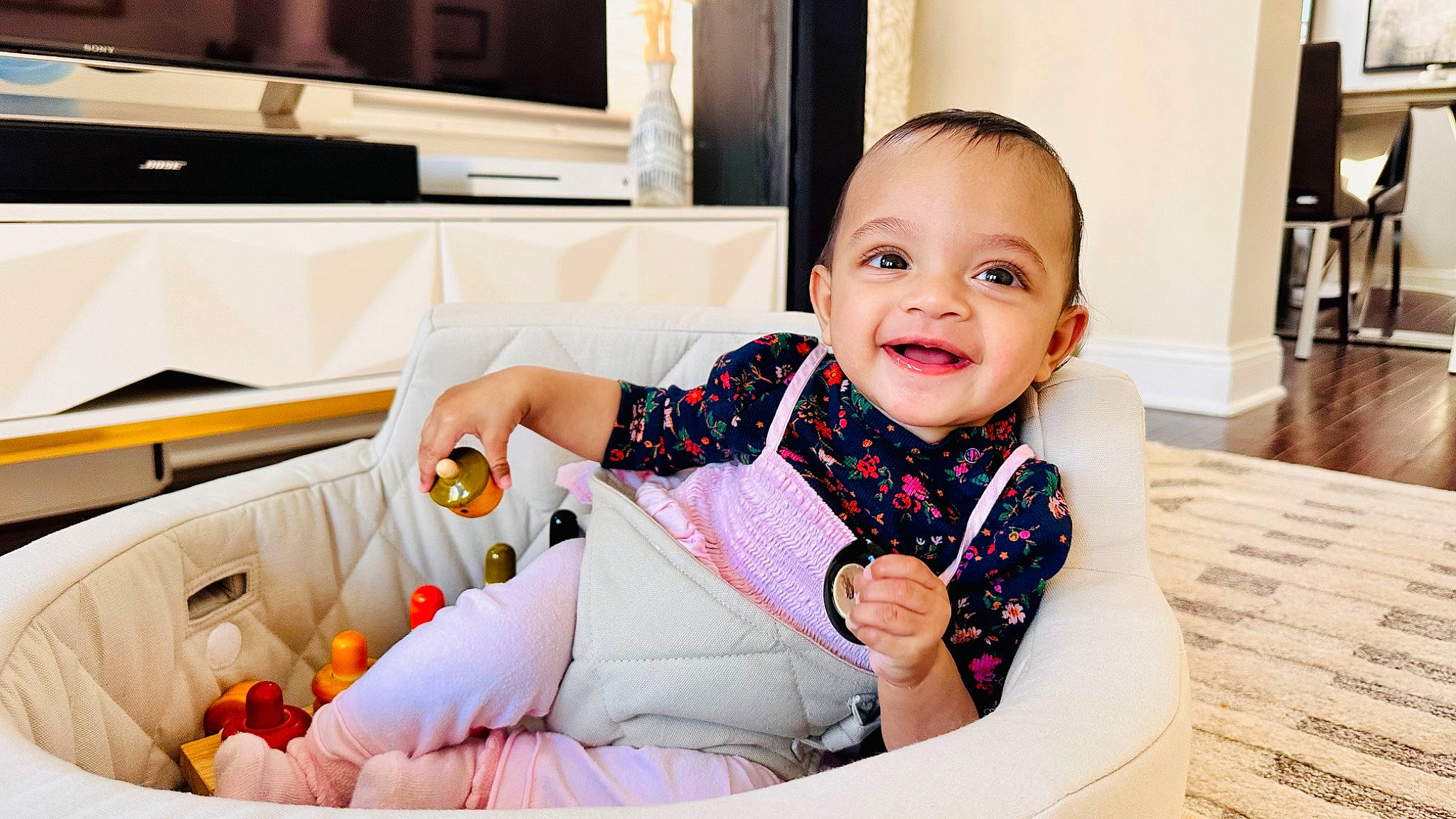 Indie is registered to the contest to win money with this photo: baby, baby_toddler_clothing, child, comfort, couch, dress, fun, happy, joy, leisure, pattern, person, portrait_photography, room, shelf, sitting, skin, sleeve, smile, sock