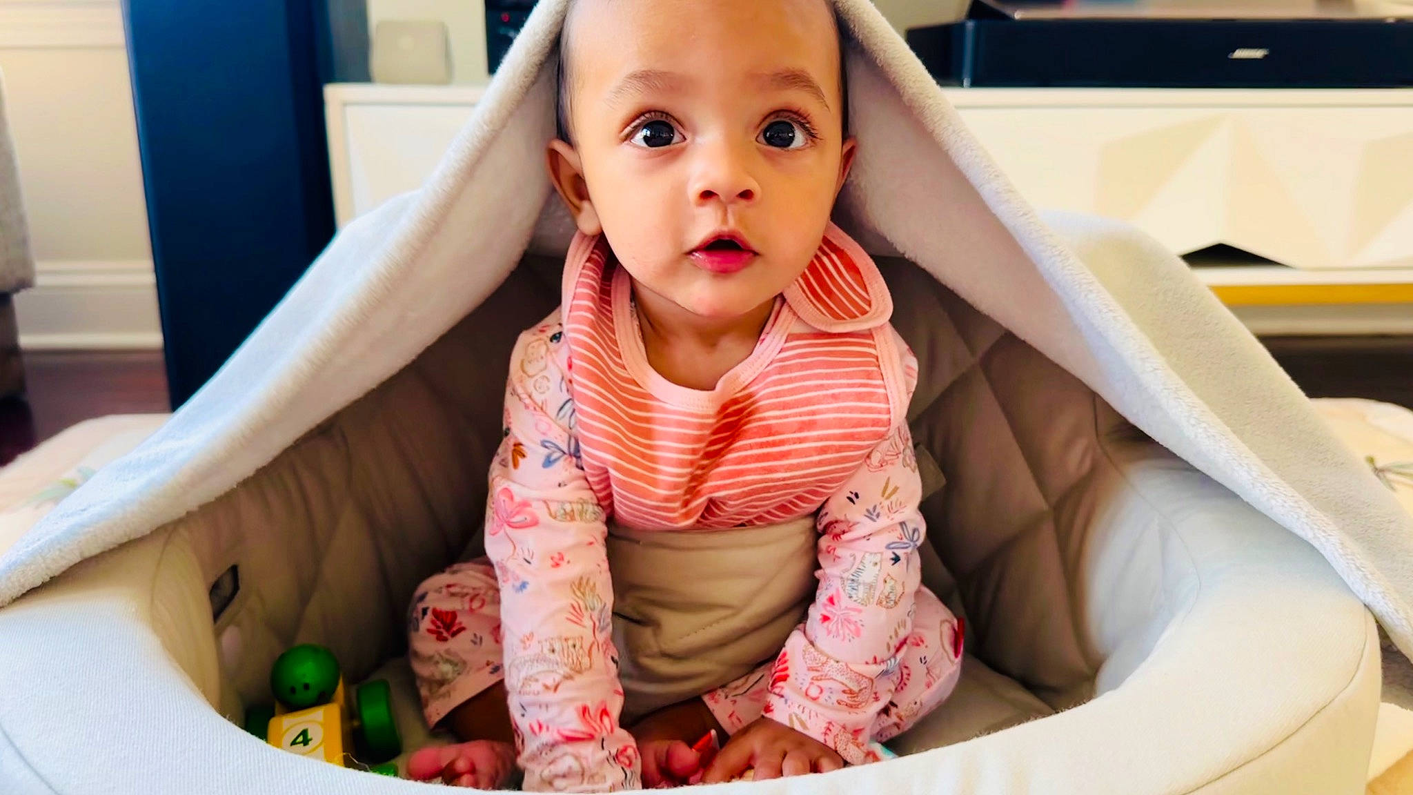 Indie is registered to the contest to win money with this photo: baby, baby_products, baby_toddler_clothing, cheek, child, comfort, face, flooring, fun, happy, leisure, mouth, nose, person, pink, product, skin, sleeve, smile, surprise