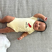 Benjamin joined the competition — help win amazing prizes! baby, infant, smiling, lying_down, onesie, yellow_clothing, chili_pepper_graphic, cute, happy, child, arm_raised, cheeks, face, skin, person, indoor, textile_background, soft_texture, playful, young
