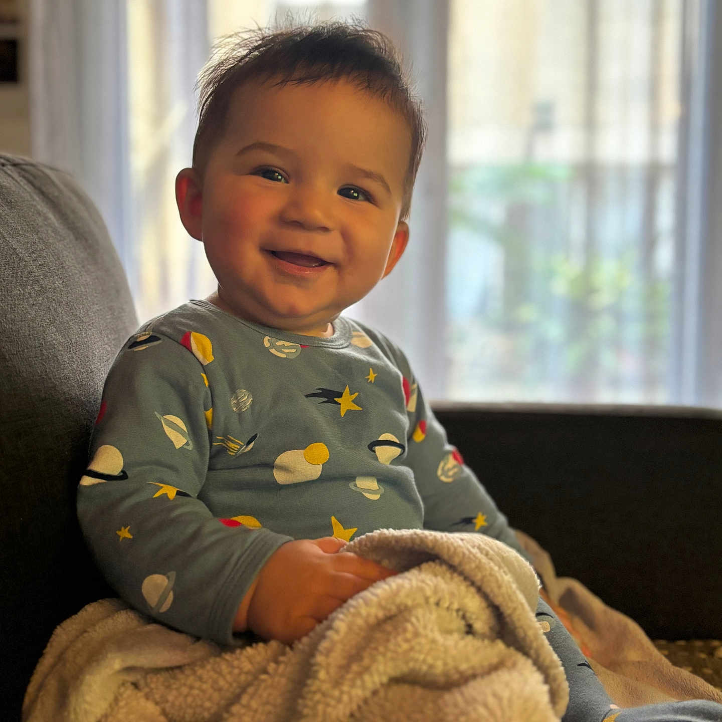 Addam a rejoint le concours — aidez-le/la à gagner de superbes lots ! baby, blanket, child, clothing, couch, cozy, curtain, face, happy, indoors, long_sleeve, planets, portrait, seated, smiling, soft_light, space_theme, stars, toddler, window