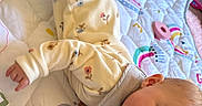 Ivy is registered to the contest to win money with this photo: baby, bib, blanket, child, clothing, colorful, cute, face, happy, indoor, infant, lying_down, pajamas, pastel, pattern, person, playful, quilt, smiling, soft