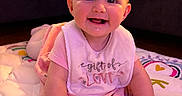 Ivy joined the competition — help win amazing prizes! baby, child, infant, smiling, face, bib, clothing, play_mat, floor, indoors, couch, happy, cute, person, portrait, young_child, pink, hand, expression, baby_girl