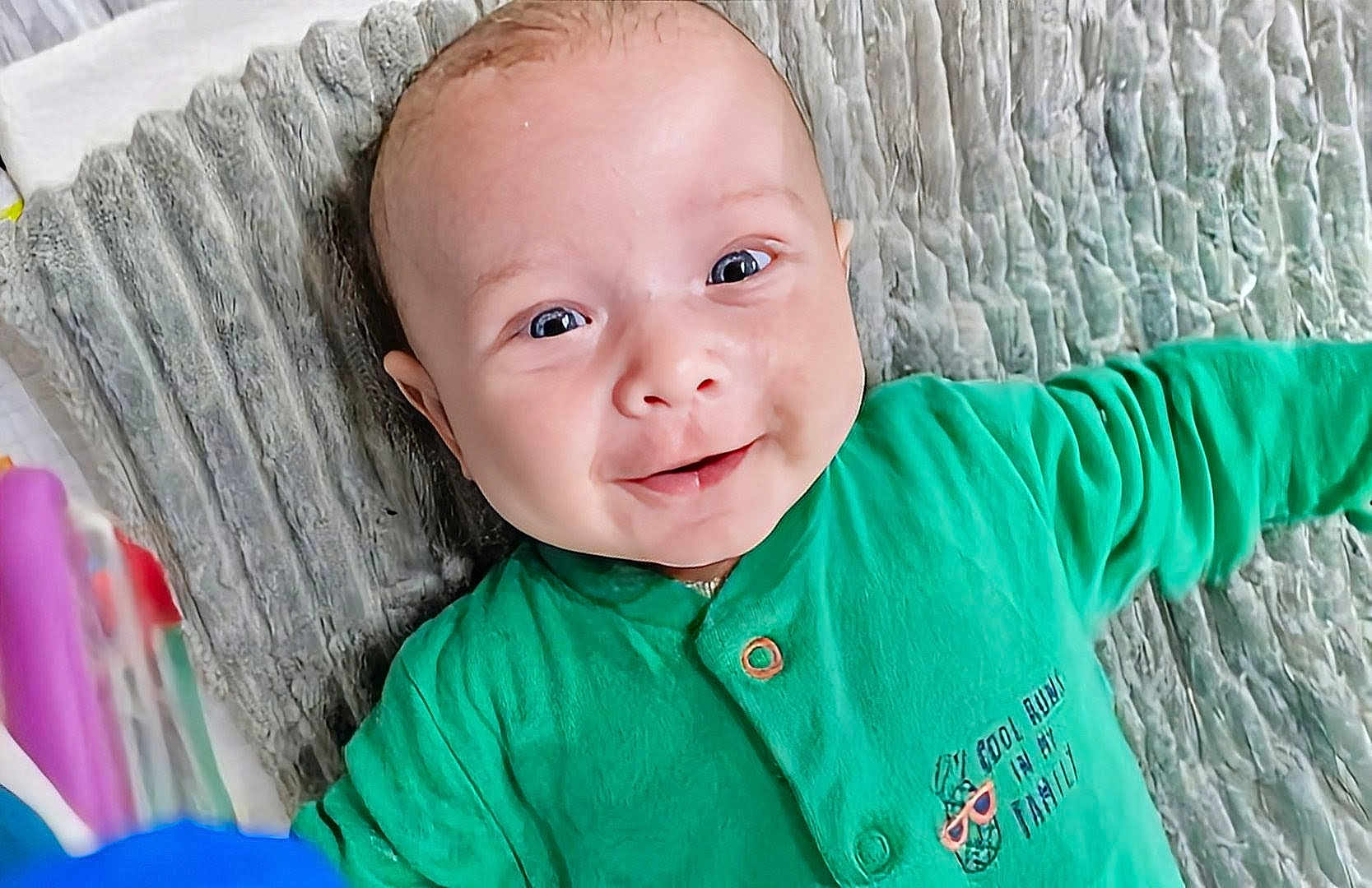 Ghilés a rejoint le concours — aidez-le/la à gagner de superbes lots ! baby, smiling, green_clothing, face, portrait, infant, happy, child, lying_down, texture, cute, young, person, indoors, expression, skin, eyes, mouth, hand, head