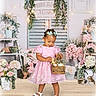 Zipporah joined the competition — help win amazing prizes! toddler, girl, pink_dress, basket, easter_eggs, flowers, floral_arrangement, ribbons, fairy_lights, bunny_figurines, wooden_floor, decor, pastel_colors, hair_bows, indoor, smiling, plant_pots, greenery, cute, spring